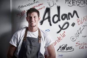 Adam-in-front-of-signed-wall-Press-Image